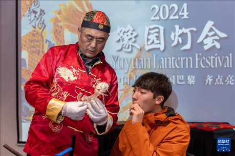 1月28日，在上海豫園舉行的民俗活動(dòng)上，美國(guó)馬斯卡廷中學(xué)學(xué)生在非遺傳承人的指導(dǎo)下吹糖偶。 新華社記者 王翔 攝