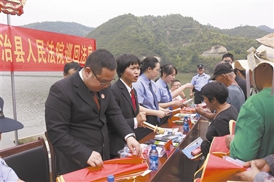 法院干警及相關(guān)部門工作人員對(duì)群眾進(jìn)行生態(tài)環(huán)境保護(hù)普法教育。