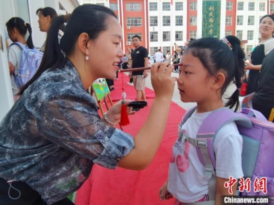 圖為衡水市利民路小學(xué)，老師為學(xué)生點朱砂痣，寓意開啟智慧。張松 攝