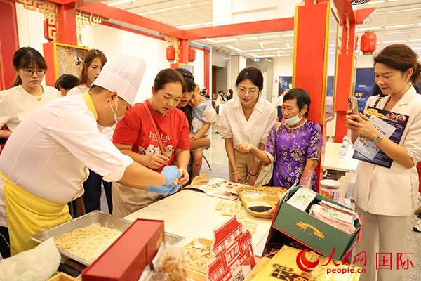 演出前，在天津桂發(fā)祥十八街麻花制作技藝非遺體驗展臺前，泰國民眾體驗天津麻花制作。人民網(wǎng)記者 楊一攝