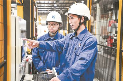 在廣西柳工機(jī)械股份有限公司生產(chǎn)車間內(nèi)，一名高級技師（右）給徒弟講解數(shù)控設(shè)備操作細(xì)節(jié)。新華社記者 曹祎銘攝