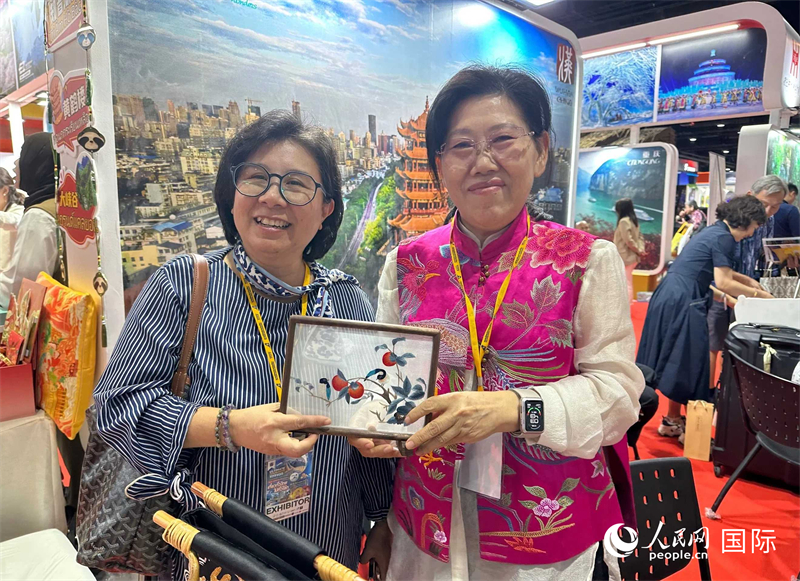 中國“大冶刺繡”傳承人劉小紅（右）參加泰國國際旅游展，向觀眾介紹中國非遺刺繡針法。人民網(wǎng)記者 簡承淵攝