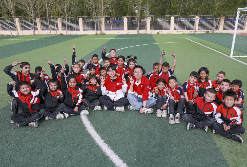 4月23日，在新疆克州阿圖什市哈拉峻鄉(xiāng)謝依特小學(xué)，支教教師王俊文（中左）、李軻凡（中右）和學(xué)生在一起。